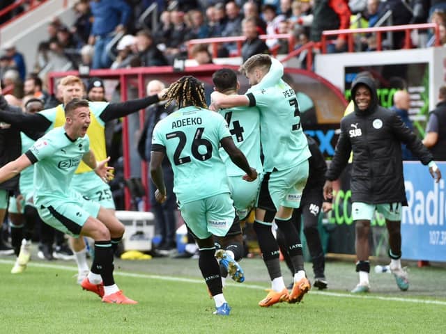 Jordan Jones is mobbed after securing Latics' 2-0 victory at Exeter