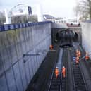 Emergency workers view a car that crashed onto tracks in Salford causing major disruption to train services