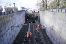 Emergency workers view a car that crashed onto tracks in Salford causing major disruption to train services