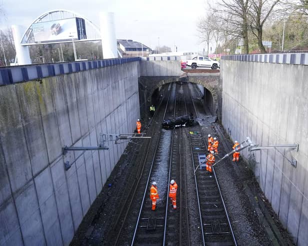 Emergency workers view a car that crashed onto tracks in Salford causing major disruption to train services
