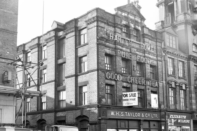The derelict warehouse of W.H.S.Taylor on Market Street, Wigan, in 1971 with Elizabeth Wilding photographic shop next door and the Queen's Hall tower just visible.