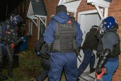 Police officers force their way into a house