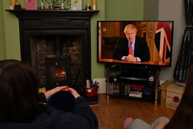 Members of a family listen as Britain's Prime Minister Boris Johnson makes a televised address to the nation from inside 10 Downing Street with the latest instructions to stay at home to help contain the Covid-19 pandemic (Photo: PAUL ELLIS/AFP via Getty Images)