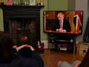 Members of a family listen as Britain's Prime Minister Boris Johnson makes a televised address to the nation from inside 10 Downing Street with the latest instructions to stay at home to help contain the Covid-19 pandemic (Photo: PAUL ELLIS/AFP via Getty Images)