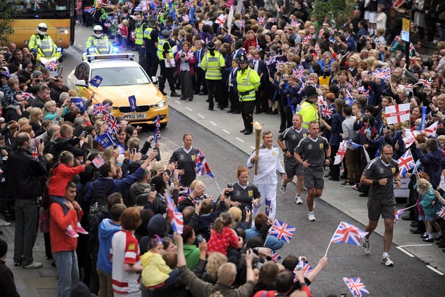 Olympic Torch Relay, Wigan Town Centre:  Norman Brown carries the Olympic Torch up Wallgate
