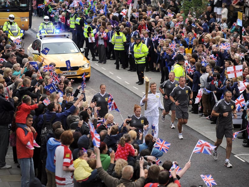 Olympic Torch Relay, Wigan Town Centre:  Norman Brown carries the Olympic Torch up Wallgate
