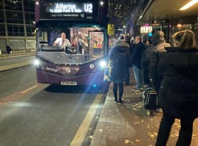 The V2 bus pulls up to a queue of people waiting to get on