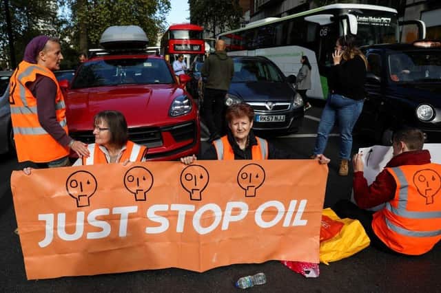 Members of the environmental activist group Just Stop Oil hold a banner as they block Park Lane, in central London