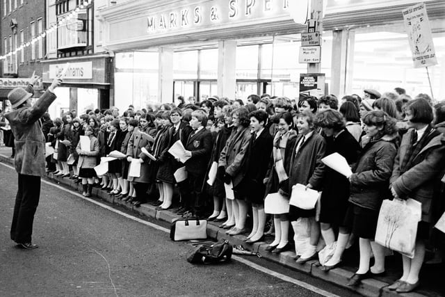 Wigan schoolchildren entertain Christmas shoppers on Standishgate, outside Marks and Spencer and Debenhams, in 1984