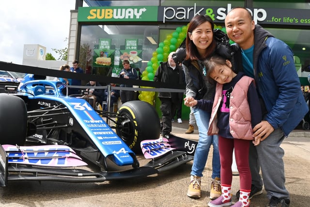 Tracy Chin, Fai Chow and Scarlett, four, pose next to the Alpine Formula One car.