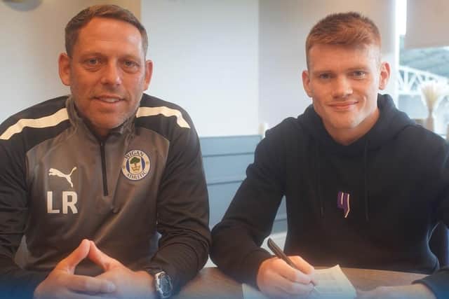 Luke Robinson puts pen to paper, watched by Leam Richardson