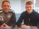 Luke Robinson puts pen to paper, watched by Leam Richardson