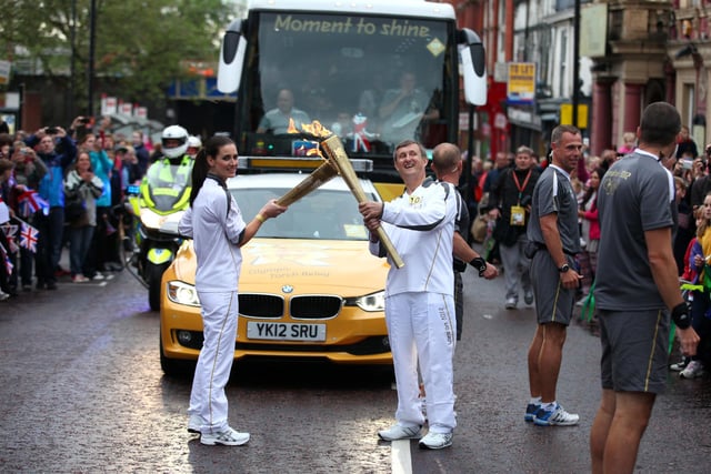 Torchbearer 100 Kirsty Gallacher passes the Olympic Flame to Torchbearer 101 Norman Brown on the Torch Relay leg between Wigan and Ince-in-Makerfield.