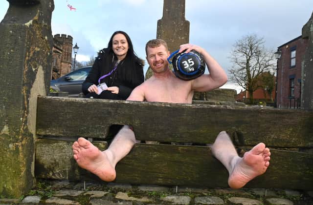 Nigel Brookwell at the stocks in Standish where he will spend the night in his latest fund-raiser, pictured with Sam Doyle, from Empathy North West