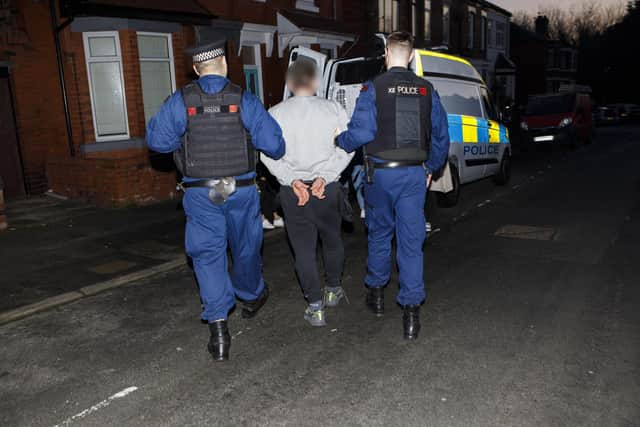 A suspect is led away after an early morning raid in Wigan