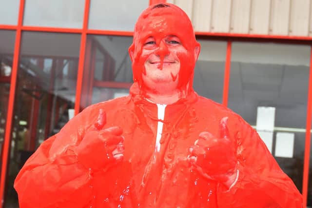 Mike Hyde smiling after going under the bucket of red slime.