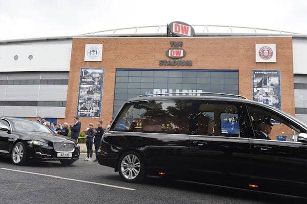 The funeral cortege of former Wigan Warriors chairman Maurice Lindsay pauses outside the DW Stadium as staff members applaud to pay their respects. The funeral was held at St Mary's Church, Standishgate, Wigan