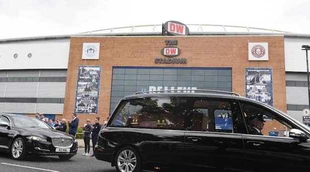 The funeral cortege of former Wigan Warriors chairman Maurice Lindsay pauses outside the DW Stadium as staff members applaud to pay their respects. The funeral was held at St Mary's Church, Standishgate, Wigan