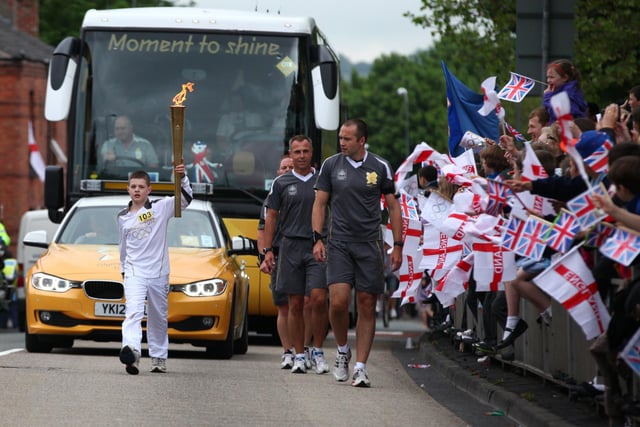 Torchbearer 103 carries the Olympic Flame on the Torch Relay leg between Wigan and Ince-in-Makerfield.