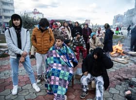 Earthquake survivors sit around a fire in Iskenderun Turkey
