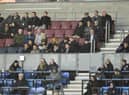 Wayne Rooney (centre of picture, wearing cap) was an interested spectator in the DW Stadium directors box on Monday night