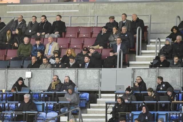 Wayne Rooney (centre of picture, wearing cap) was an interested spectator in the DW Stadium directors box on Monday night