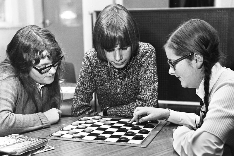 Janet Gaskell, left, and Anne Halliwell enjoy a game of draughts watched by John Kinley at Penson Street Youth Club, Swinley, on Tuesday 31st of October 1972.