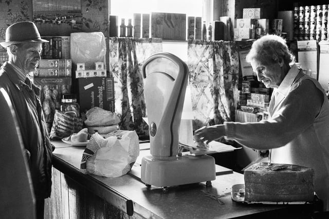 Janie Geller weighs out some boiled ham for a customer in her grocery shop in Up Holland Road, Billinge, in July 1988.