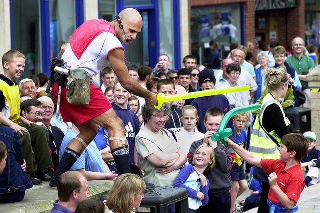 Loco Brusco is challenged to a balloon sword fight in Market Place during the Wigan Maydayze Festival on Saturday 26th of May 2001.