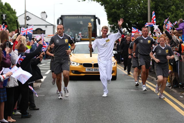 Torchbearer 095 Andrew Cowley carries the Olympic Flame on the Torch Relay leg between Wigan and Ince-in-Makerfield.