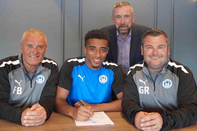Joe Rodwell-Grant signs for Latics, watched by Frankie Bunn, Mal Brannigan and Gregor Rioch