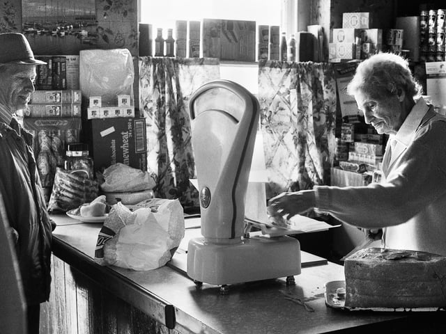 Janie Geller weighs out some boiled ham for a customer in her grocery shop in Up Holland Road, Billinge, in July 1988.