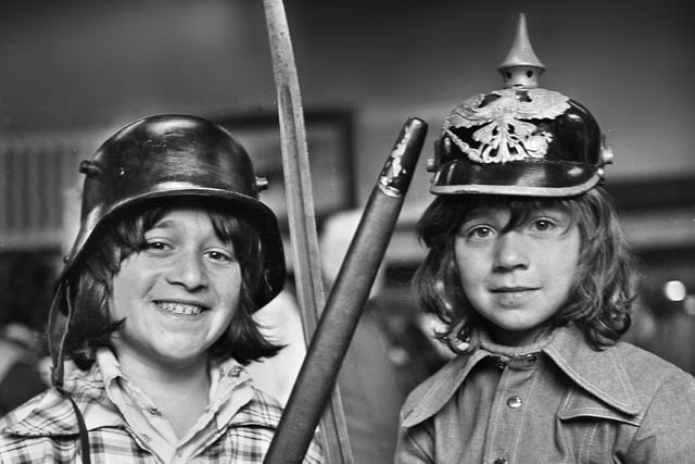 Maurice Cohen wearing a World War One German steel helmet and sister Michelle sporting a German Pickelhaube which they spotted at a flea market in the Queen's Hall, Wigan, on Saturday 24th of May 1975.