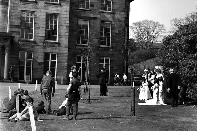 It's 1969 and a group of boys pause their game of football to watch a wedding party pose for photographs at Haigh Hall