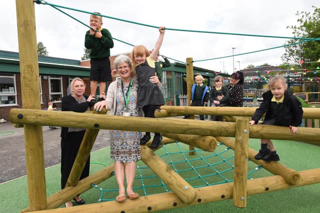 Headteacher Gillian Leigh, centre, with staff and excited school pupils enjoying their new play area.