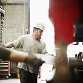 Steel workers placing sheet of steel in large brake press
