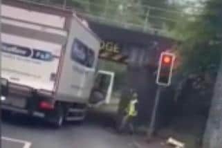 The driver out of his cab judging whether his lorry fits under the Prescott Street bridge. His assessment proved wrong.
