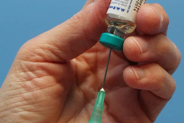 A nurse uses a syringe to prepare an injection of the MMR vaccination