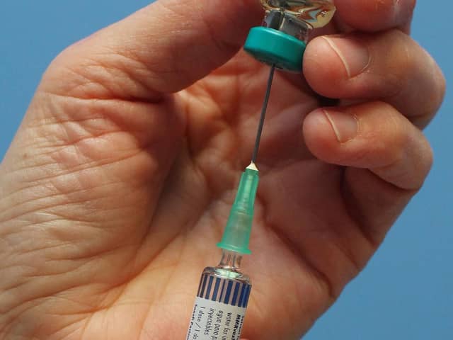 A nurse uses a syringe to prepare an injection of the MMR vaccination