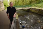 Coun George Davies with the trolleys thrown into the River Douglas
