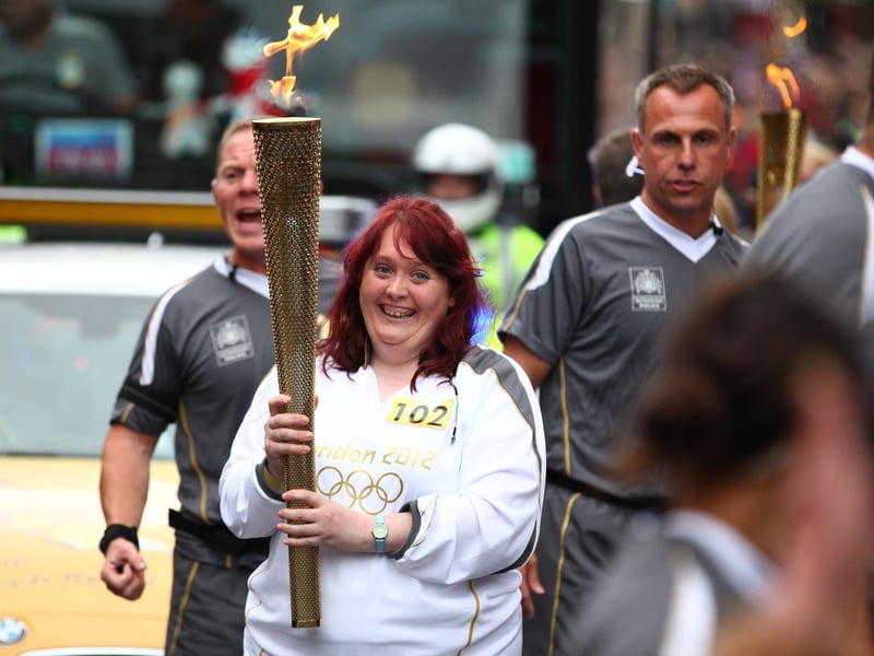 Torchbearer 102 Hazel Johnson carries the Olympic Flame on the Torch Relay leg between Wigan and Ince-in-Makerfield.