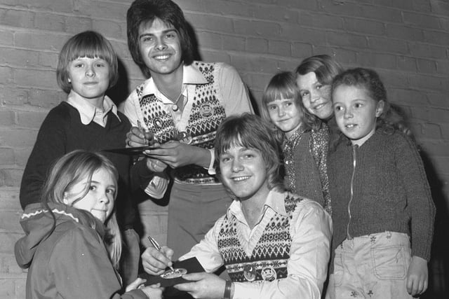 A pop duo sign autographs for young fans at the ABC cinema, Wigan, in 1976.