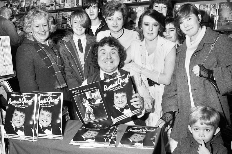 Celebrity astrologer Russell Grant signing copies of his prediction book for customers at Smith's bookshop on Mesnes Street on Wednesday 21st of December 1983.