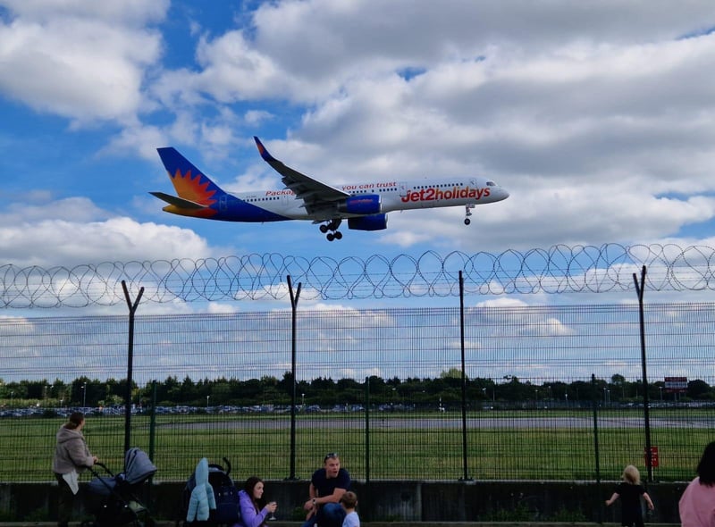 A plane prepares to land as people watch on in the beer garden