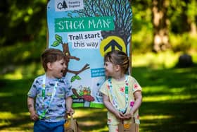 Two children standing in front of a Stick Man activity trail panel.