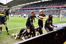 The Latics players celebrate in front of a packed away end