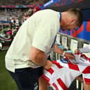 Owen Farrell signs a Wigan Warriors shirt before England's recent World Cup match against Japan in France