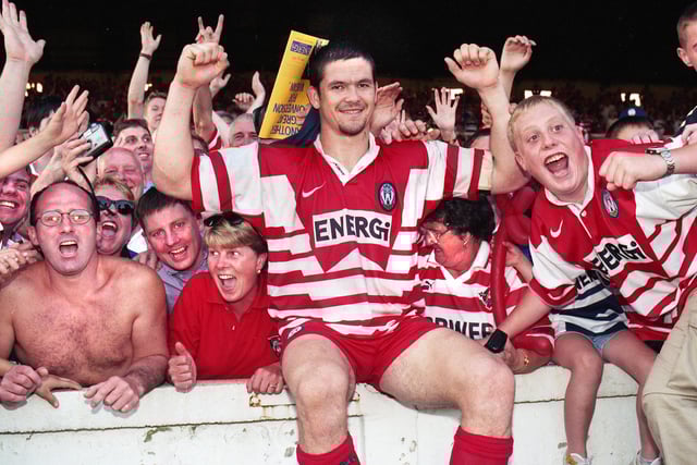 Andy Farrell sits on the wall to celebrate with fans after the match.