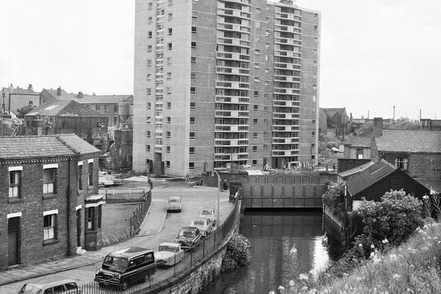 Looking over the River Douglas towards the newly built Woodcock House flats with cars parked in Derby Terrace in July 1966.