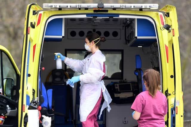 Staff wearing PPE of gloves and face masks, as a preactionary measure against COVID-19, disinfect an ambulance after it arrived with a patient at St Thomas' Hospital in north London (Photo: DANIEL LEAL-OLIVAS/AFP via Getty Images)